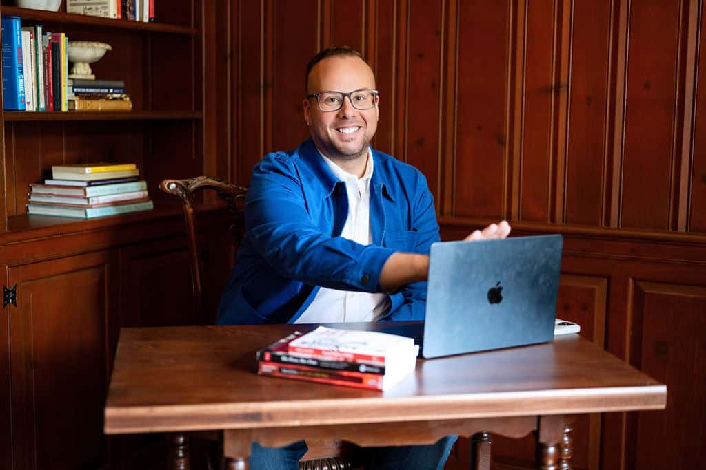 Dr. Mike, sitting at his desk opening his laptop, shares helpful resources for men's sexual health and wellness.