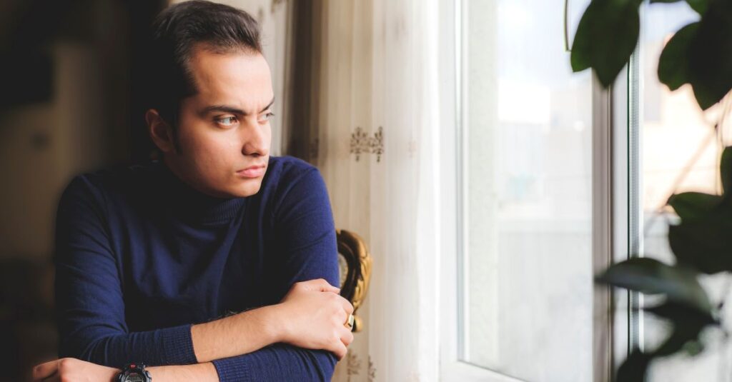 Man lost in thought looks out the window.